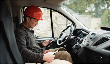 Lioton 1000 at work, A man wearing a red hardhat, sitting in a work truck, checking his phone.